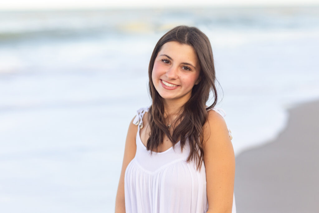 close up headshot of Vero Beach High School Senior wearing a white dress with the ocean in the background