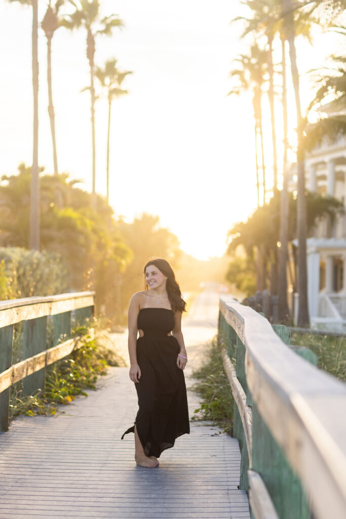 Vero Beach High School Senior Portrait wearing black dress on a boardwalk with palm trees in the background