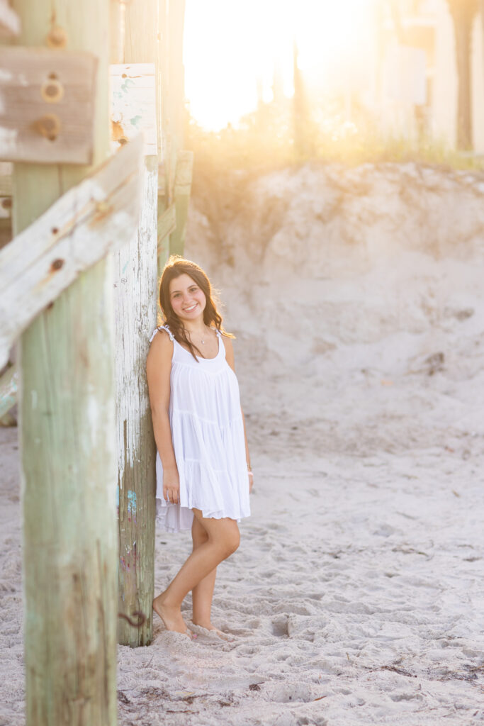Vero Beach High School Senior Photos on the beach wearing white dress under a boardwalk