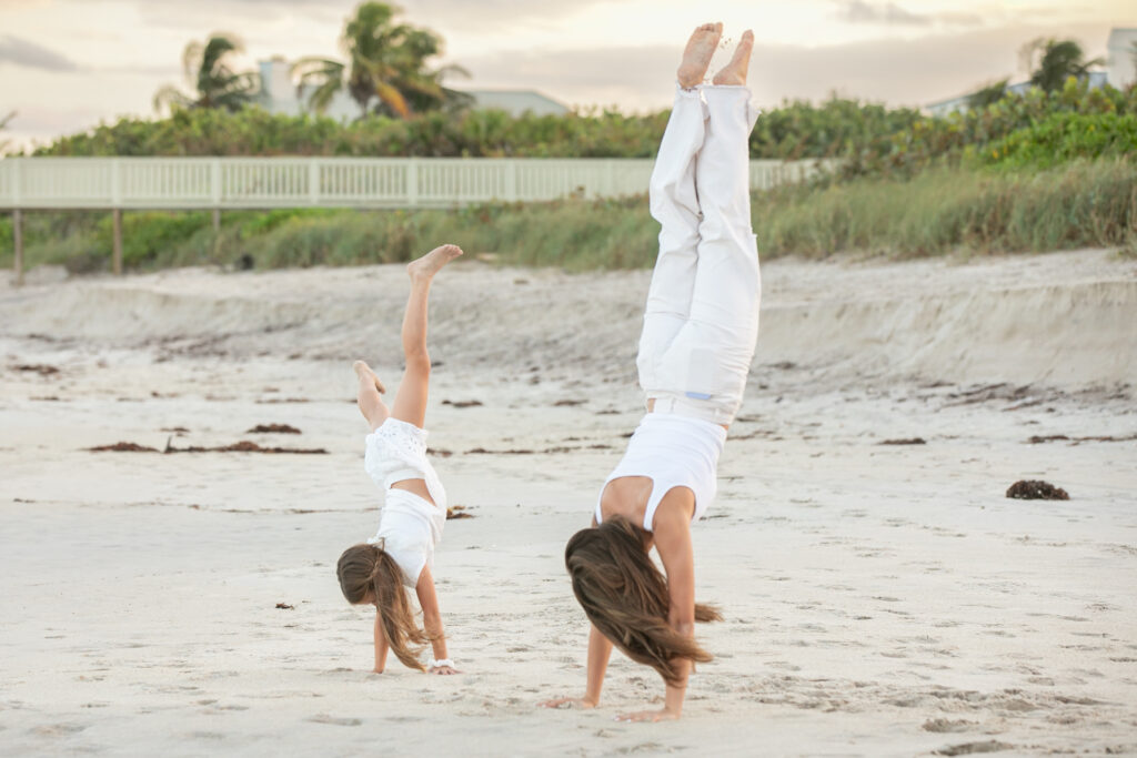 candid photo of cousins doing handstand on the sand in Vero Beach Florida