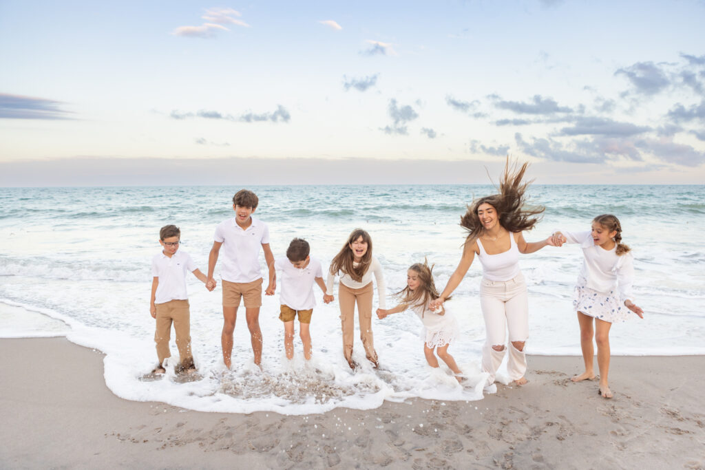 silly portrait of cousins jumping the air and in the ocean waves in Vero Beach Florida