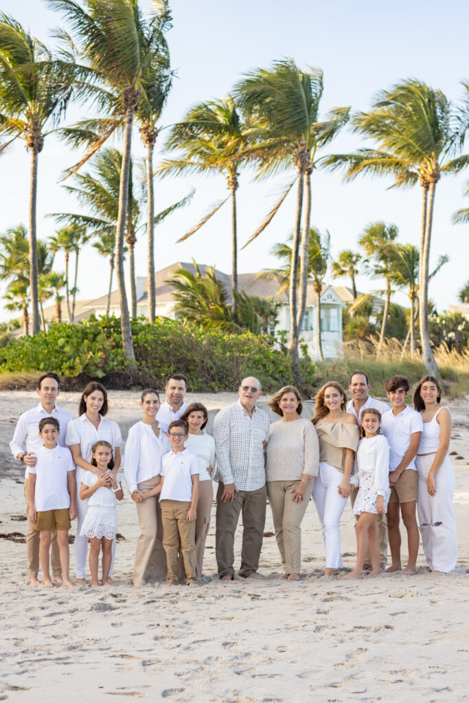 portrait of large gathering a family wearing white and khaki on the beach with palm trees Moorings Vero Beach Florida