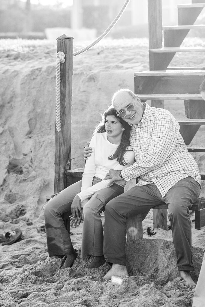 black and white photo of a grandfather hugging granddaughter while sitting on the steps of the boardwalk