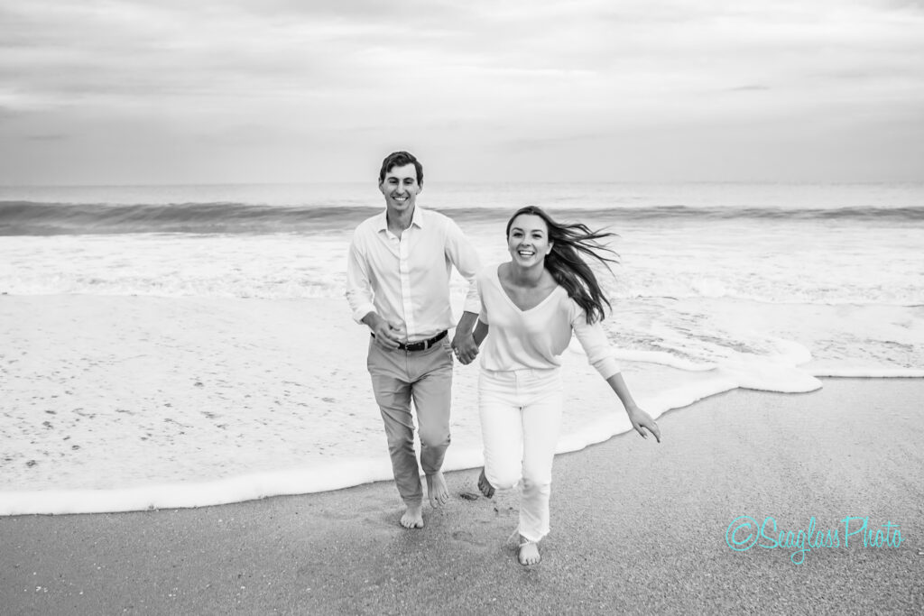 black and white photo of beautiful couple running away from the ocean waves in Vero Beach Florida 