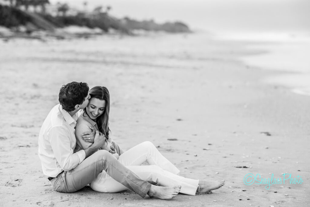 engagement photo of couple sitting on the sand in Vero Beach Florida