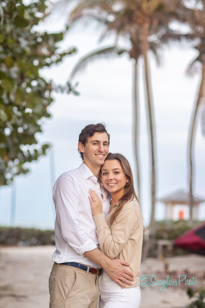 portrait of couple standing in front of palm trees on the beach at the John's Island Beach Club in Vero Beach Florida