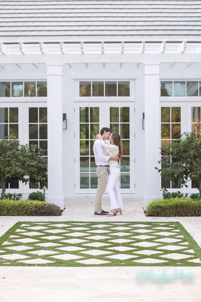 young couple kissing each other on a beautiful patio with decorative grass and pergola in John's Island FLorida 