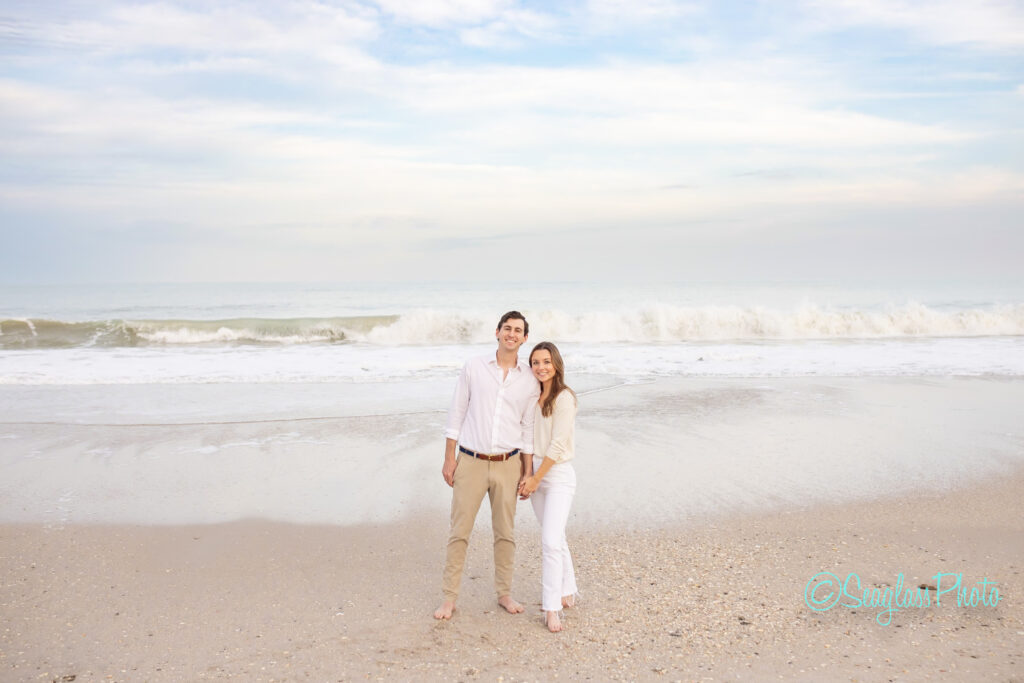 portrait of an adorable couple standing on Vero Beach with ocean waves crashing behind them