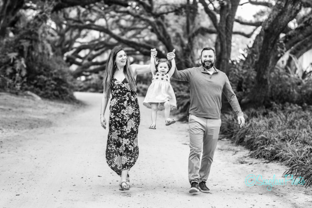 Black and white Portrait of parents playing with their daughter and dog under the oaks on Sandfly Lane Vero Beach Florida