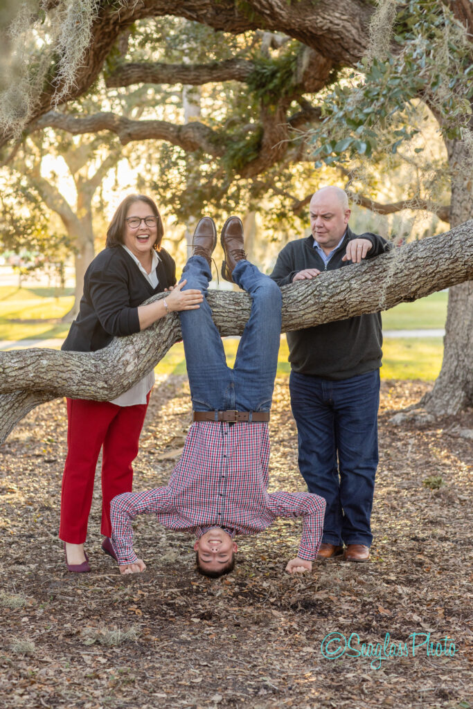 mom is laughing while her son hangs upside down from an old oak tree next to Riverside Theater in Vero Beach Florida