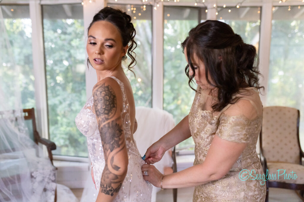 mother helping her daughter into her wedding gown 