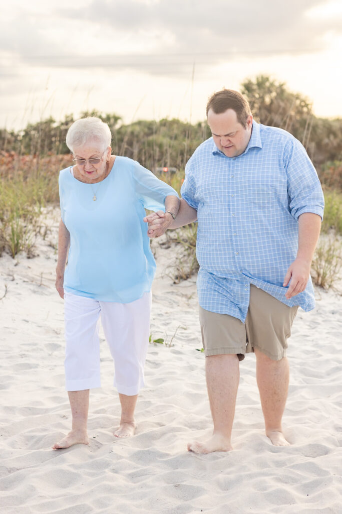 grandson helping his grandmother walk on the beach 