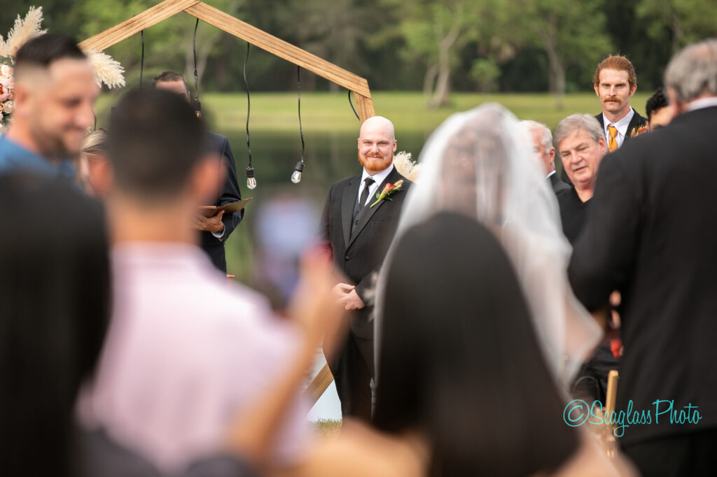 a groom looking at his bride as she walks down the aisle at a backyard wedding in Vero Beach, Florida 