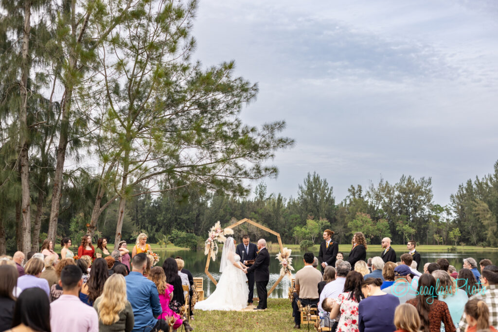 a wedding ceremony set up in front of a lake in the woods in Vero Beach Florida 