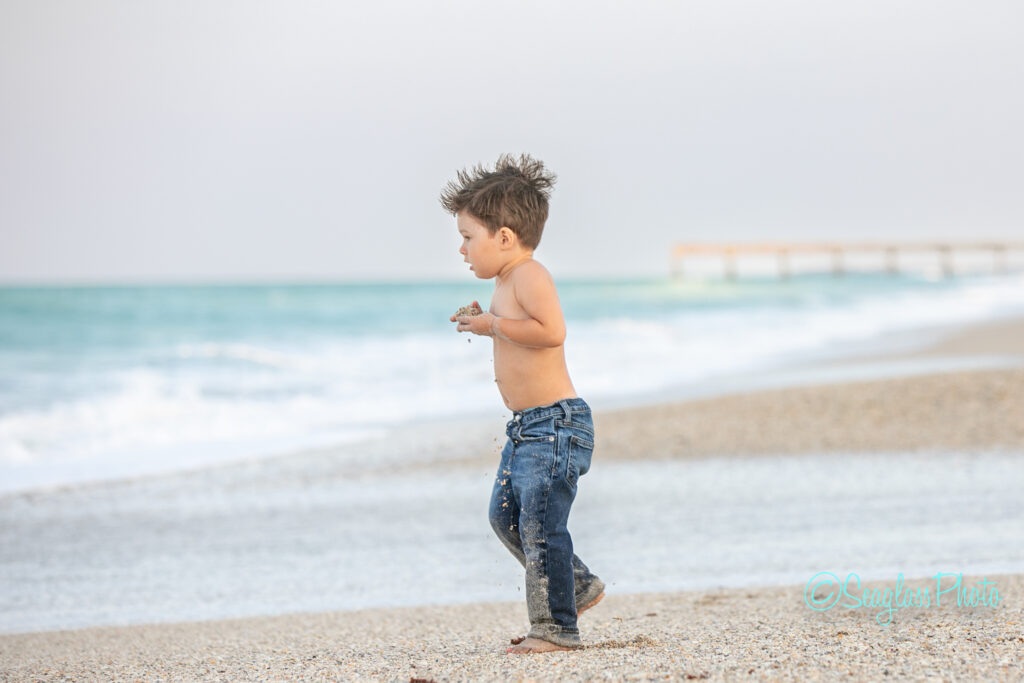 kid wearing jeans and a mohawk carrying sand to the ocean by the pier in Vero Beach Florida 