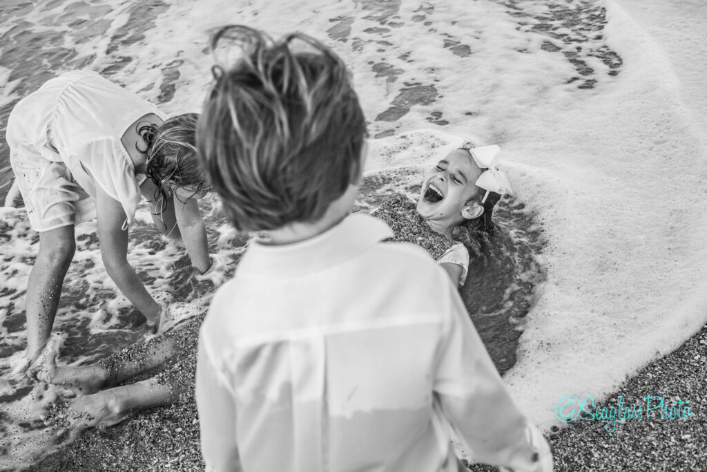 black and white photo of kids playing in the sand with the waves crashing  in Vero Beach Florida 