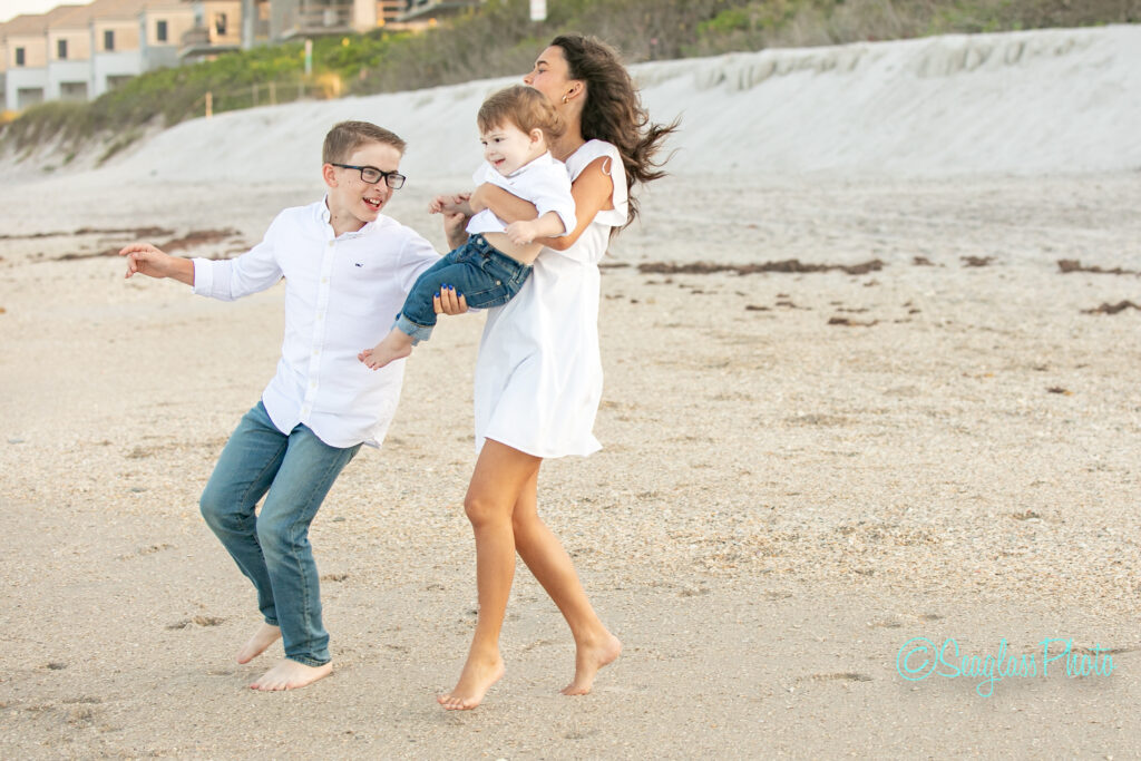 kids wearing white and jeans running on the beach towards the ocean in Vero Beach Florida 