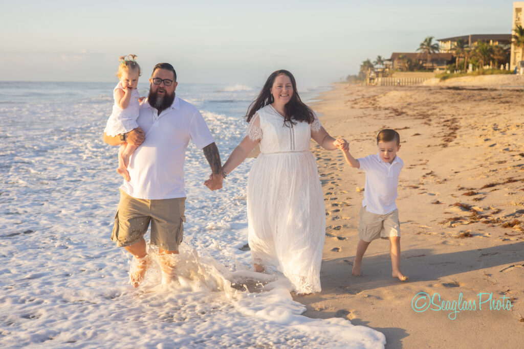 Family running through the ocean waves at sunrise in front of Costa D'Este in Vero Beach 