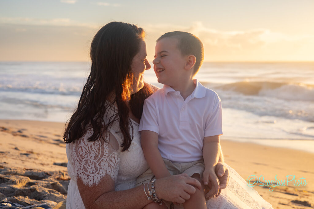 mother and son sitting on the beach overlooking the ocean at sunrise in Vero Beach Florida during a family photography session 