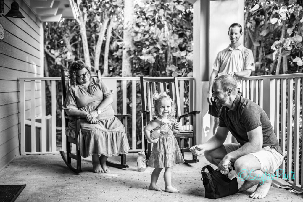 black and white photo of grandma sitting in a rocking chair on a front porch at Disney Vero Beach Resort watching her grandaughter