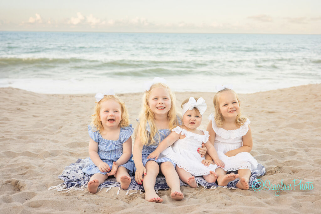 photoshoot of sisters wearing blue and white sitting on the sand at the Disney Vero Beach Resort