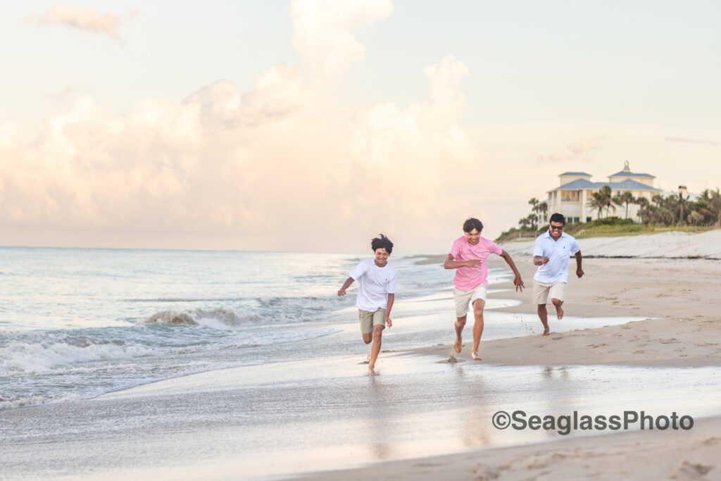 father and sons at the Disney Vero Beach Resort running on the shore at sunset during a family photoshoot