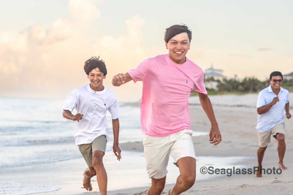 father and sons at the Disney Vero Beach Resort running on the shore at sunset during a family photoshoot