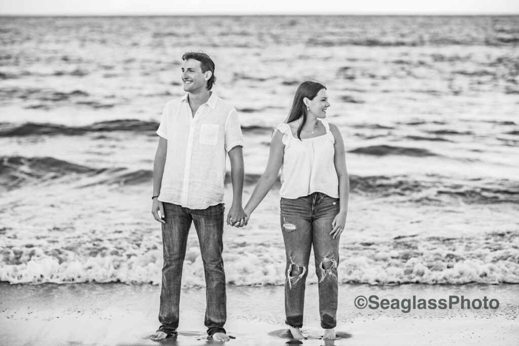 black and white engagement photo of couple holding hands looking in opposite direction