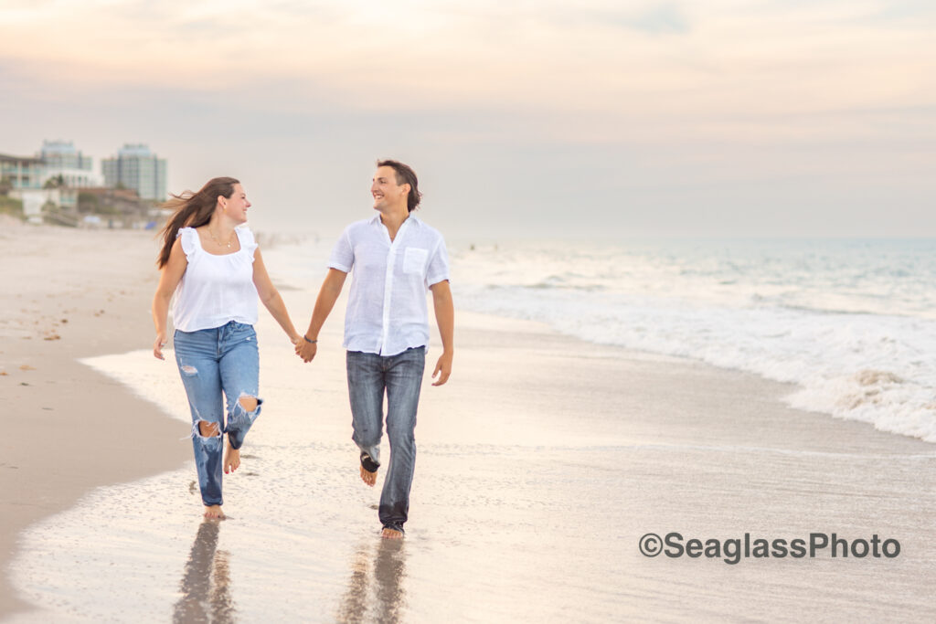 couple wearing white shirts and jeans running down the beach at sunset in Vero Beach Florida engagement photoshoot