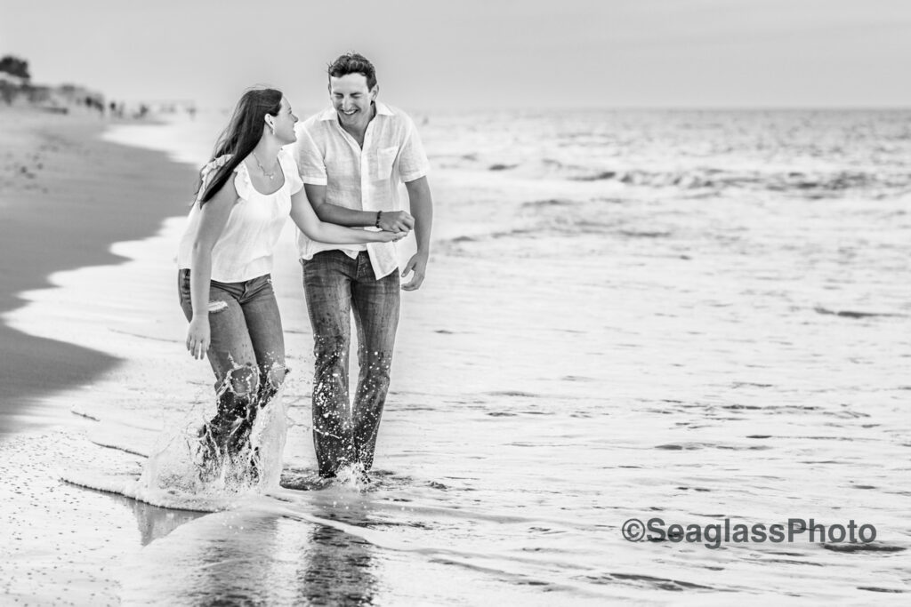 Black and White Photo of couple wearing white shirts and jeans laughing on the  beach in Vero Beach Florida engagement photoshoot