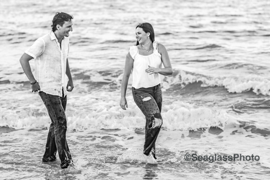 Black and White Photo of couple wearing white shirts and jeans laughing on the  beach in Vero Beach Florida engagement photoshoot