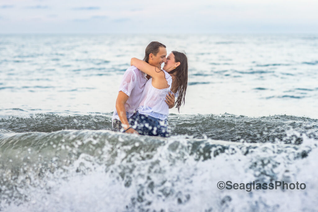 couple wearing white shirts and jeans kissing in the water in Vero Beach Florida engagement photoshoot