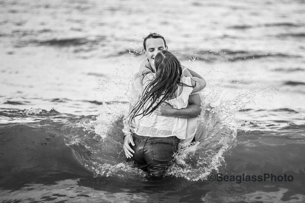 black and white photo couple being splashed by the waves in Vero Beach Florida engagement photoshoot