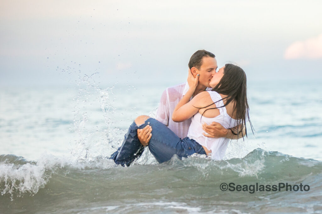 couple kissing while being splashed by the waves engagement photoshoot in Vero Beach Florida 