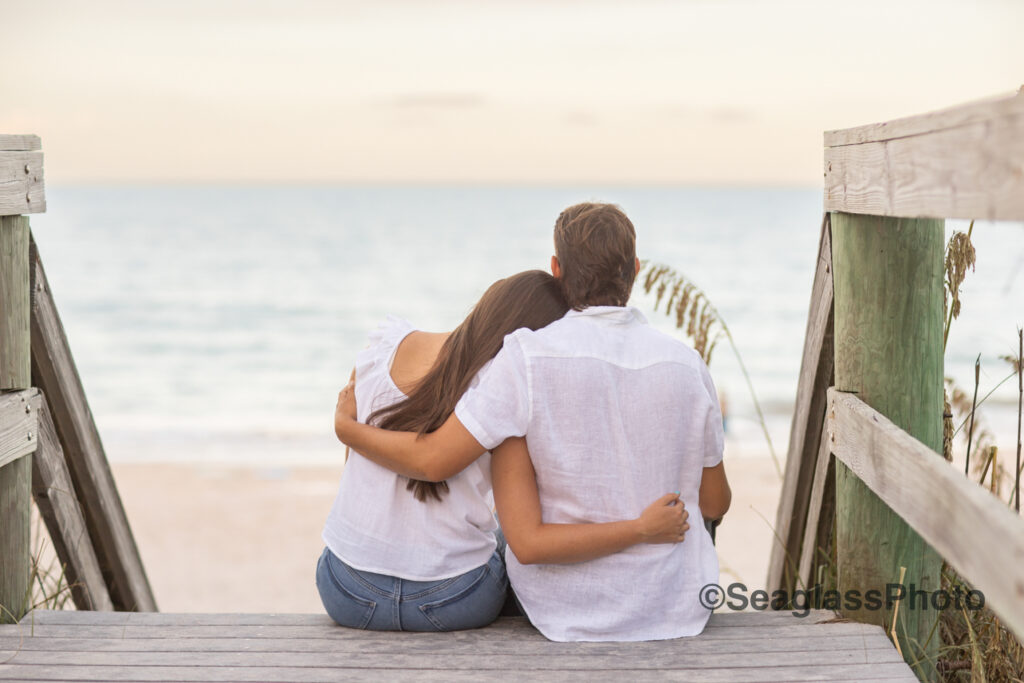 Engaged Couple sitting at the end of a boardwalk in Vero Beach Fl overlooking the ocean