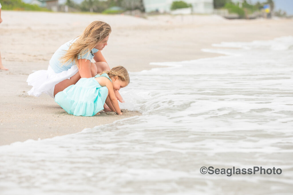 sisters wearing white and aqua playing on the waters edge at the Vero Beach Disney Resort