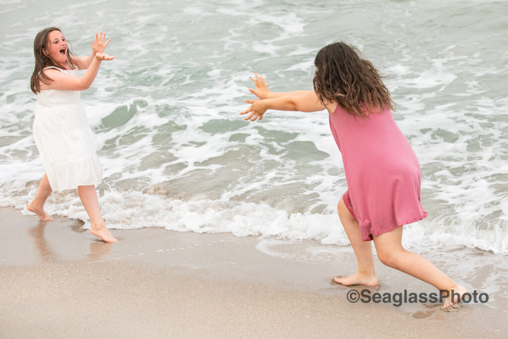 sisters wearing white and pink playing at the ocean at the Vero Beach Disney Resort