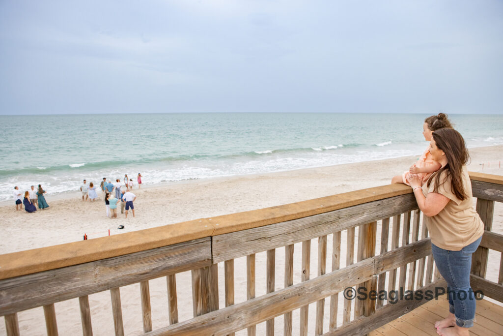 mother and daughter standing on the wooden deck at the Disney Vero Beach Resort overlooking her family playing on the beach