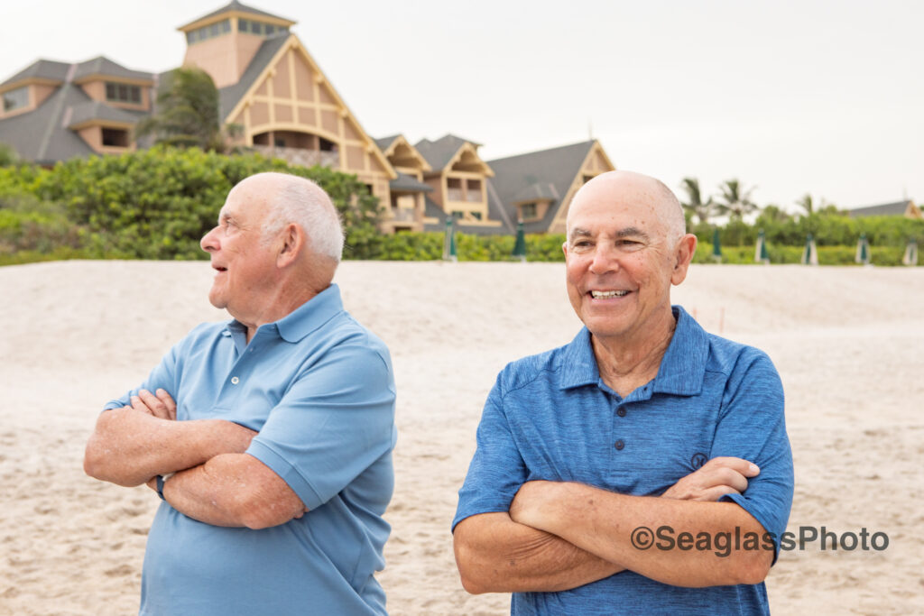 Elderly men standing in front of the Vero Beach Disney Resort wearing blue  with arms crossed
