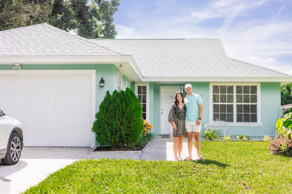 young couple standing in front of their first time home buyer in Vero Beach Florida on a beautiful day with blue skies